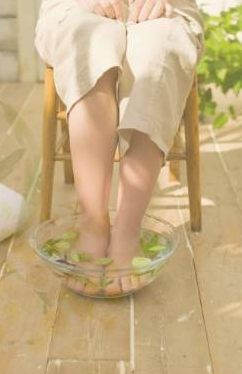 木の床に置いたガラスの器で足浴をしているところ。窓から光が入っている